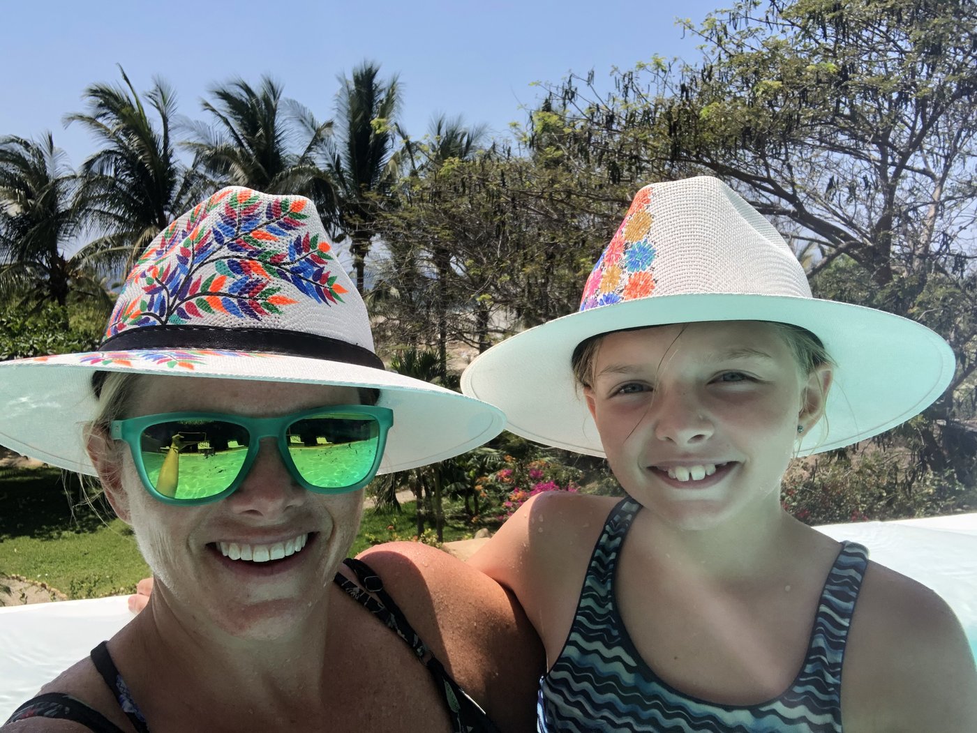 A mother-daughter selfie in matching straw hats