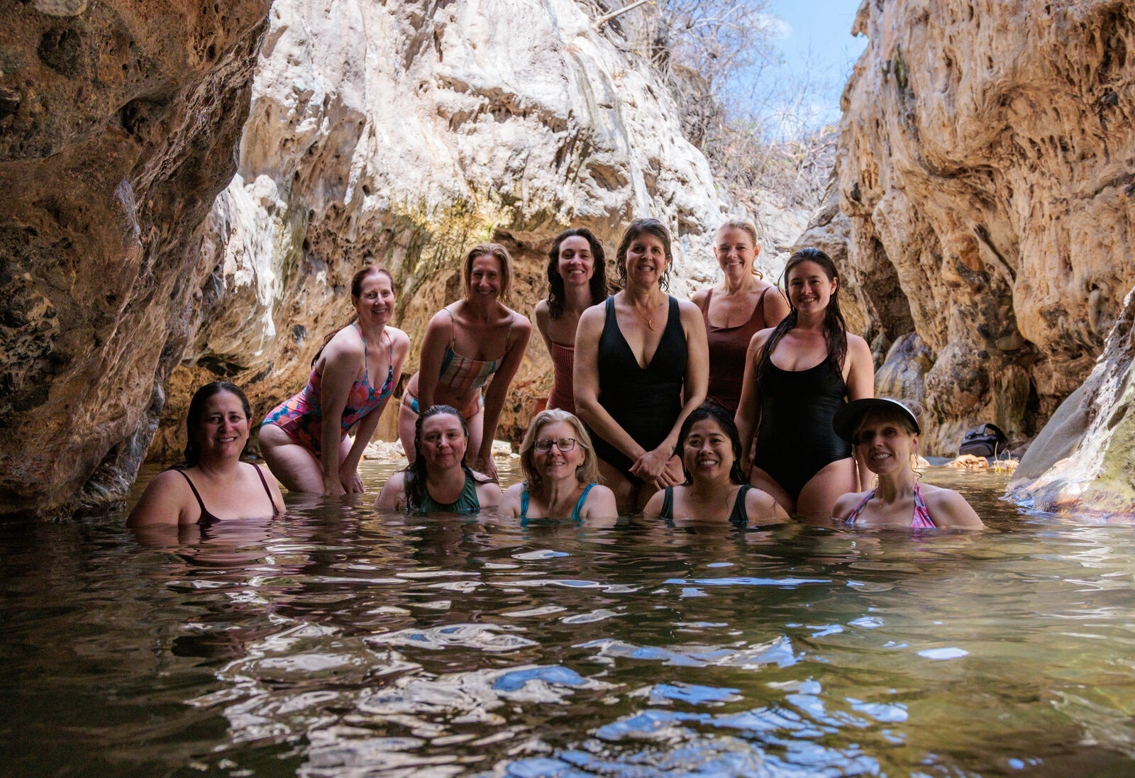 The group smiling together in a limestone canyon pool
