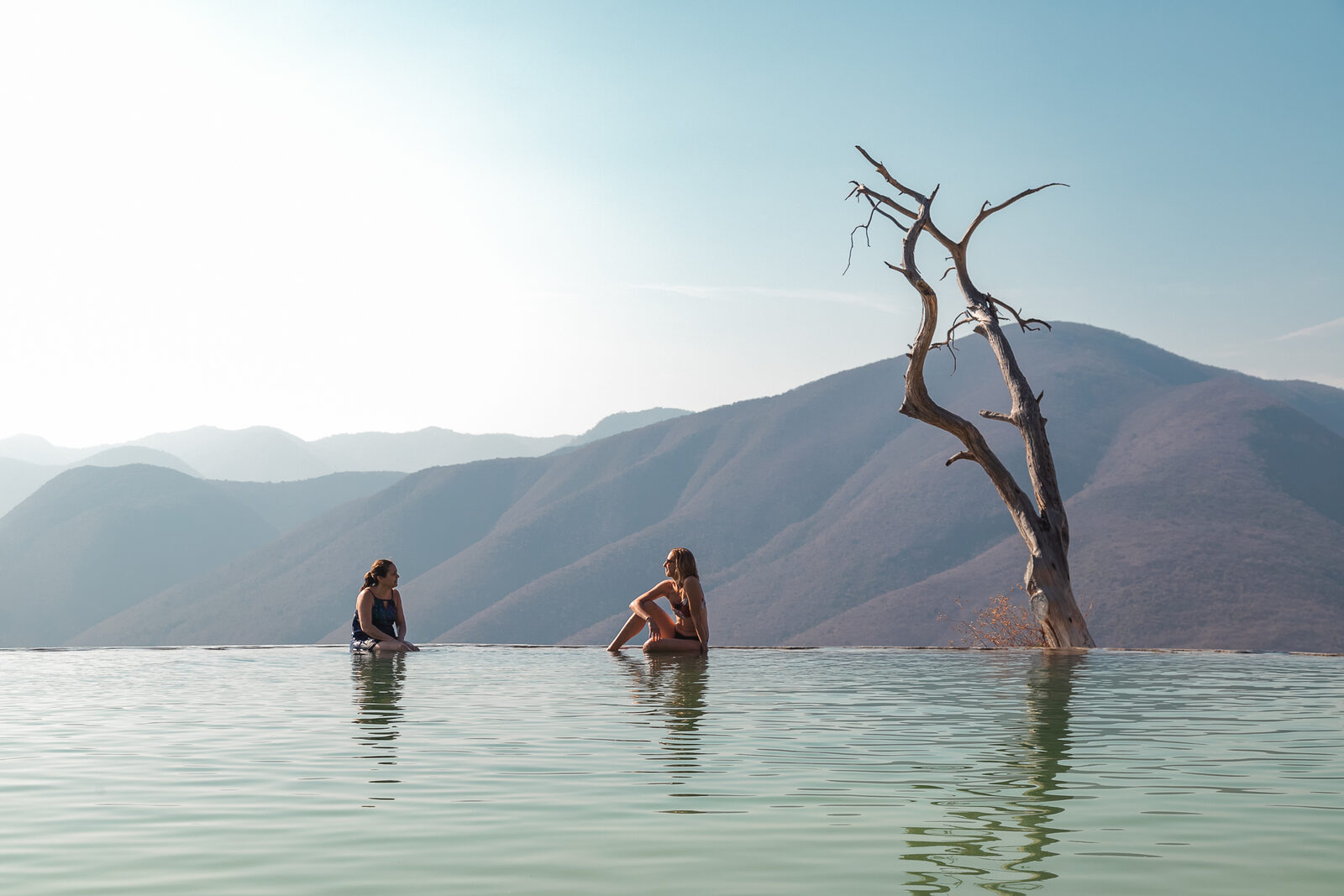 Two women sitting at the edge of the infinity pool at Hierve el Agua