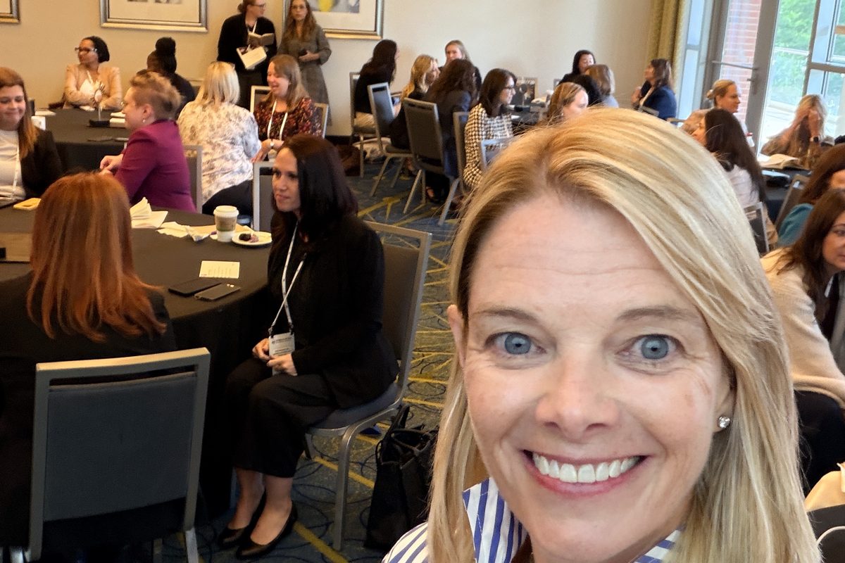 Suzanne facilitating a workshop with women leaders seated at round tables