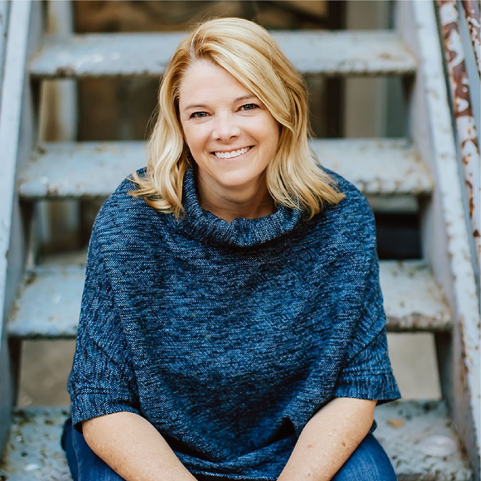 Suzanne Roske smiling, seated on a set of steel stairs